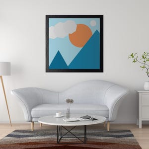 Puede incluir: Una impresión abstracta enmarcada de un cielo azul con una nube blanca, un sol naranja y montañas azules. La impresión está colgada en una pared blanca sobre un sofá blanco.