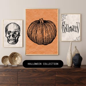 Puede incluir: Tres impresiones de arte de pared imprimibles con temática de Halloween. La primera impresión presenta una calavera en blanco y negro. La segunda impresión presenta una calabaza en blanco y negro sobre un fondo naranja. La tercera impresión presenta la palabra "Halloween" en escritura negra con un diseño de telaraña.