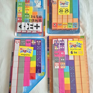 Könnte beinhalten: Vier Numberblocks Bausätze in Originalverpackung. Die Sets enthalten bunte Kunststoffbausteine mit aufgedruckten Gesichtern und Zahlen, darunter Themen für die Zahlen 1 bis 5, 16 bis 20, 20 bis 25 sowie ein Set mit verschiedenen Zahlenblöcken.