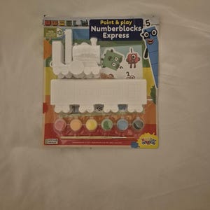 May include: A paint and play Numberblocks Express set. The kit includes a white plastic train and paint pots in various colors. The packaging features Numberblocks characters and the text "Paint & play Numberblocks Express".