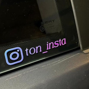 Peut inclure: Gros plan sur une vitre de voiture avec un logo Instagram violet et bleu et le texte "ton_insta" dessus.