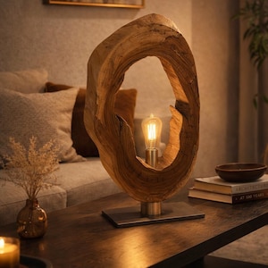 May include: A distinctive wooden table lamp. The lamp has a large, organic-shaped wooden frame with a warm lightbulb at its centre. The lamp sits on a dark metal base, adding a touch of modern elegance. The lamp is approximately 40 cm tall.