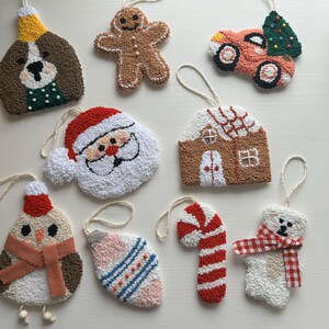 May include: A collection of handmade Christmas ornaments in various shapes, including a dog, gingerbread man, car with a tree, Santa Claus, house, owl, teardrop, candy cane, and polar bear. Each ornament is made with textured yarn and has a loop for hanging.