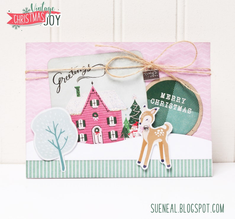 May include: A pink and white Christmas card with a house, a deer, a tree, and the words "Greetings" and "Merry Christmas".