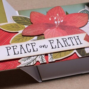 May include: A handmade card with a red, white, and green floral design. The card has a banner that says "Peace on Earth".