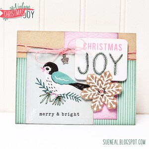 May include: A Christmas card with a vintage design featuring a blue bird on a branch, a snowflake, and the text "Christmas Joy" and "merry & bright".