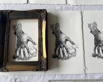 May include: An ornate, gold-framed artwork featuring a detailed black and white illustration of a hand-like tree with a castle on top. Several unframed prints of the same artwork are also visible, showcasing the artist's work.