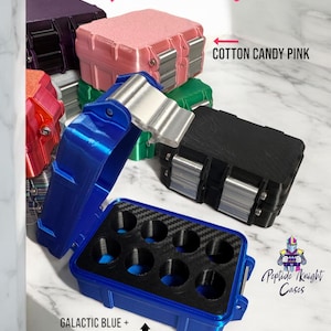 May include: A collection of small, colorful cases in various shades, including pink, blue, green, and black. The cases have silver clasps and are labeled "Cotton Candy Pink" and "Galactic Blue + Carbon Interior." The text "8ct - 3mil" is also visible.
