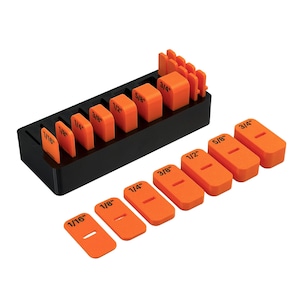 May include: A set of orange setup blocks with black printed measurements ranging from 1/16 inch to 3/4 inch. The blocks are stored in a black rectangular base, with additional matching orange blocks laid out in a row in front of the storage unit.