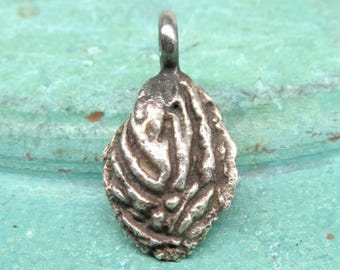 May include: A silver charm in the shape of a seashell with a textured surface.