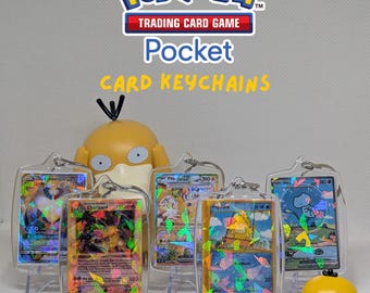 May include: A collection of clear acrylic keychains containing miniature Pokémon trading cards with holographic foil details. The text MINI POKEMON TRADING CARD GAME Pocket CARD KEYCHAINS is displayed above two yellow Psyduck figurines.