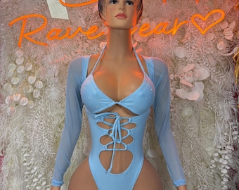 May include: A light blue bodysuit with long sheer sleeves and a lace-up front. The swimsuit has cut-out details and is embellished with small rhinestones. The mannequin is in front of a wall with the neon text "Rave Year".