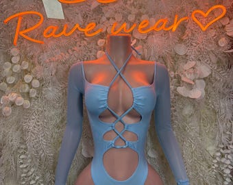 May include: Light blue bodysuit with long sheer sleeves and cut-out details. The halter-style top features criss-cross ties and a keyhole design. The background includes the neon text "Rave wear".