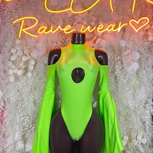 May include: Neon green bodysuit with long, flared sleeves and a keyhole cutout. The high-neck design features shoulder cutouts. The words "PLUR Rave wear" are in neon yellow script above the bodysuit.