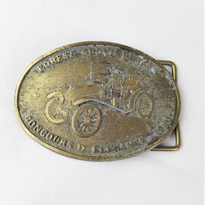 May include: A brass belt buckle featuring a vintage car with the text "Forest Grove Run 1910 Concours D'Elegance 1930".