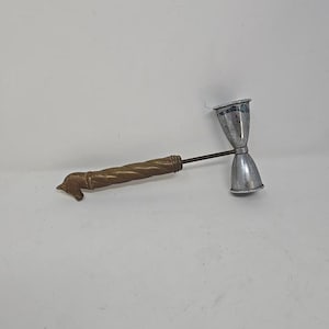 Könnte beinhalten: Ein Vintage-Cocktail-Jigger mit einem messingfarbenen Griff mit einem Pferdekopf-Design. Der Jigger hat zwei silberfarbene Messbecher, die durch einen dünnen Metallstab verbunden sind, zum Messen von Flüssigkeiten für Cocktails.