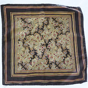 Op de afbeelding: Een bruine zijden zakdoek met een paisley-patroon in goud, rood en wit. De zakdoek heeft een donkerbruine rand met gouden en rode versieringen.