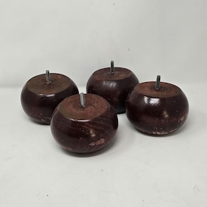 Puede incluir: Cuatro patas de mueble redondas de madera marrón rojizo oscuro con inserciones de tornillo metálicas. Las patas tienen un acabado liso y pulido y están diseñadas para el soporte de muebles. La veta de la madera es visible, lo que añade a la estética natural.