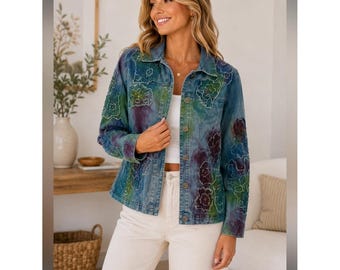 May include: A blue denim jacket featuring a tie-dye wash in shades of green and purple, accented with embroidered floral outlines. The jacket has a collared neckline, long sleeves, and a front button closure, worn over a plain white top.