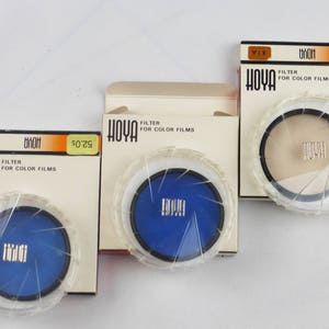 May include: Three Hoya brand camera lens filters in their original packaging. The filters are 52mm in size and are labelled "Filter for Colour Films".