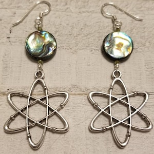May include: A pair of silver earrings with a silver atom charm and a round iridescent abalone shell bead.