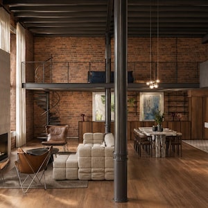 Puede incluir: Interior de loft espacioso con paredes de ladrillo visto, chimenea y entrepiso. El espacio cuenta con un sofá moderno, mesa de comedor y sillas mariposa. La habitación tiene grandes ventanales y suelo de madera.