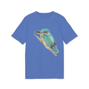 Op de afbeelding: Een blauw t-shirt met een gedetailleerde illustratie van een kleurrijke vogel die op een tak zit. De vogel heeft een groen lichaam, blauwe vleugels en een roodbruine kop. De achtergrond is effen blauw.