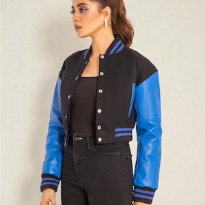 May include: A black and blue cropped varsity jacket with a blue leather sleeve. The jacket has a button closure and a ribbed collar, cuffs, and hem.