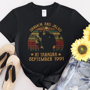 Puede incluir: Camiseta negra con un gráfico de estilo vintage de dos hombres con el texto "DARMOK AND JALAD AT TANAGRA SEPTEMBER 1991".