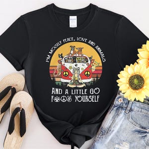 Puede incluir: Camiseta negra con un gráfico de una furgoneta retro llena de perros y gatos, rodeada de girasoles. El texto dice: "Soy principalmente paz, amor y animales, y un poco vete a la m***a".