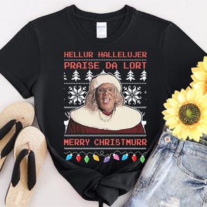 Könnte beinhalten: Schwarzes T-Shirt mit einem weißen Weihnachtspullover-Design, das eine Frau mit Brille und den Text "Hellur Hallelujer Praise Da Lort Merry Christmurr" zeigt.