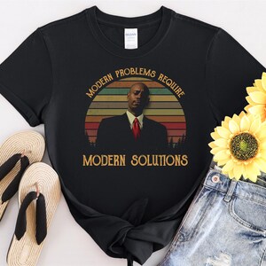 May include: Black t-shirt with a vintage-style graphic of a man in a suit with the text "Modern Problems Require Modern Solutions".