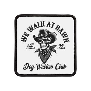 May include: Black and white patch featuring a skull wearing a cowboy hat and bandana. The text reads "We Walk At Dawn est 99 Dog Walker Club".