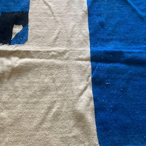 Peut inclure: Un tapis tiss&eacute; avec un motif blanc et bleu. Le tapis est fait de fibres naturelles et a une surface douce et textur&eacute;e.