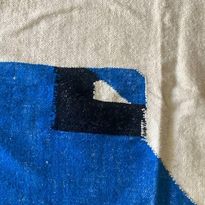 Peut inclure: Gros plan sur un tapis tiss&eacute; avec un motif g&eacute;om&eacute;trique. Le tapis est fait de fibres naturelles et pr&eacute;sente une palette de couleurs blanche, bleue et noire.