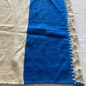 Peut inclure: Un tapis tiss&eacute; blanc et bleu avec des franges sur les bords. Le tapis est fait d'un mat&eacute;riau doux et textur&eacute;.