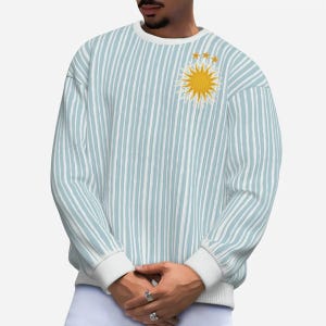 May include: A light blue striped sweater with a yellow embroidered sun and three stars.