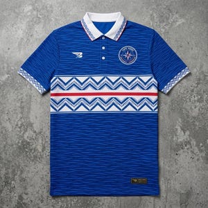 Puede incluir: Polo azul con cuello y mangas blancos, con un patrón de ondas. La camisa tiene una franja blanca y roja en el pecho, con un emblema circular que dice "CAPE VERDE".