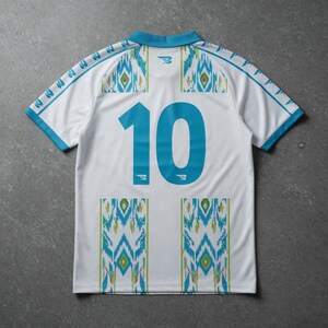 May include: White soccer jersey with turquoise accents and the number 10 on the back. The jersey features a geometric pattern in turquoise, green, and yellow. The collar and sleeves are trimmed in turquoise.