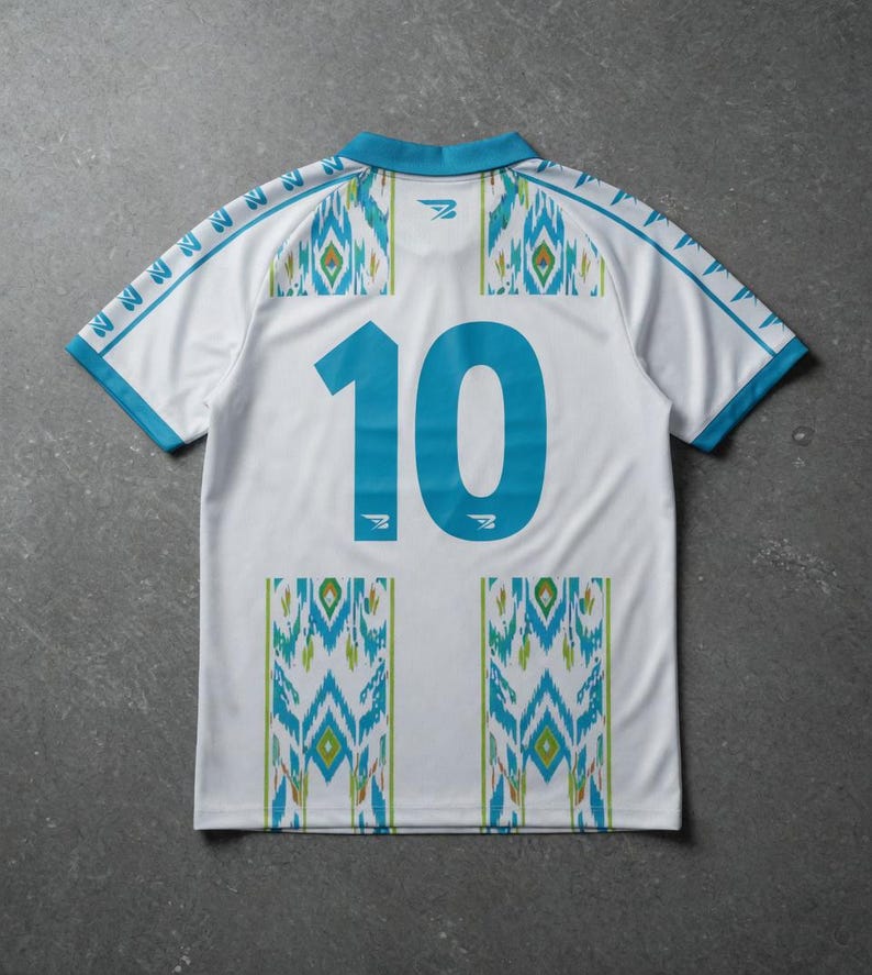 May include: White soccer jersey with turquoise accents and the number 10 on the back. The jersey features a geometric pattern in turquoise, green, and yellow. The collar and sleeves are trimmed in turquoise.