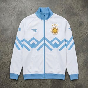 May include: White track jacket with light blue accents, a full zipper, and a stand-up collar. The jacket features a geometric design in light blue across the chest and sleeves, along with a sun emblem and three stars on the chest. The jacket has a sporty aesthetic.