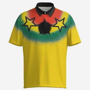 Puede incluir: Polo amarillo con cuello negro y mangas cortas. La camiseta presenta un dise&ntilde;o con estrellas rojas, verdes y negras, y un efecto de pintura en aerosol en el pecho. La camiseta tiene una tapeta abotonada.