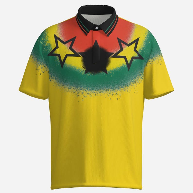 Puede incluir: Polo amarillo con cuello negro y mangas cortas. La camiseta presenta un dise&ntilde;o con estrellas rojas, verdes y negras, y un efecto de pintura en aerosol en el pecho. La camiseta tiene una tapeta abotonada.