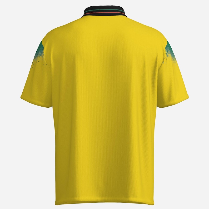 Puede incluir: Un polo amarillo con cuello negro con rayas verdes y rojas. Los hombros tienen un dise&ntilde;o de salpicaduras de pintura azul y verde. La camisa tiene mangas cortas y un dise&ntilde;o de polo cl&aacute;sico.