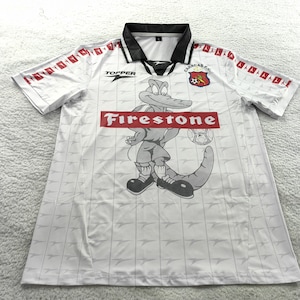 May include: White football shirt with a black collar and red detailing. The shirt displays a cartoon alligator mascot with a football, and the word "Firestone" in red. The team logo is on the chest.