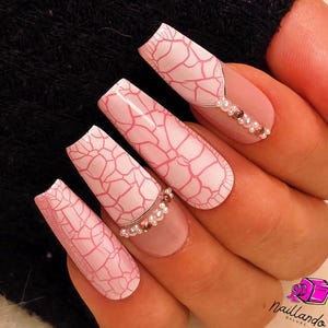 Könnte beinhalten: Rosa-weißes Craquelé-Nageldesign mit silbernen und perlmuttartigen Akzenten. Die Nägel sind lang und in Sargform.