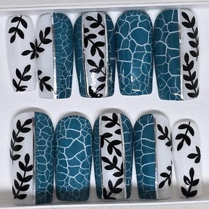 Könnte beinhalten: Set mit zehn falschen Nägeln mit einem türkisfarbenen und weißen Design. Die Nägel haben eine weiße Basis mit schwarzen Blattdesigns und eine türkisfarbene Craquelé-Oberfläche auf der einen Hälfte.
