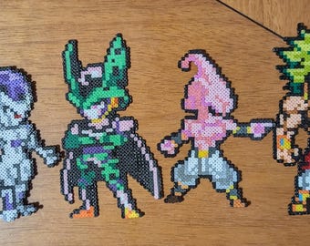 May include: Four colorful pixel art figures of Dragon Ball Z characters: Frieza, Cell, Majin Buu, and Broly. Each figure is made of small, fused plastic beads, with detailed designs and vibrant colors. The figures are displayed on a wooden surface.