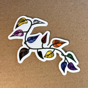 Puede incluir: Una pegatina con una vid estilizada con hojas coloridas. Las hojas son de varios colores, incluyendo amarillo, morado, azul, rojo y marrón, con un borde blanco. La vid es verde y tiene un diseño artístico y caprichoso.