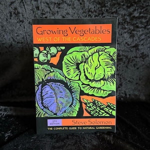 Może przedstawiać: Książka zatytułowana "Growing Vegetables West of the Cascades" zawiera kolorową ilustrację warzyw. Okładka ma czarne tło z pomarańczowymi i zielonymi akcentami. Autorem jest Steve Solomon. To przewodnik po naturalnej uprawie warzyw.